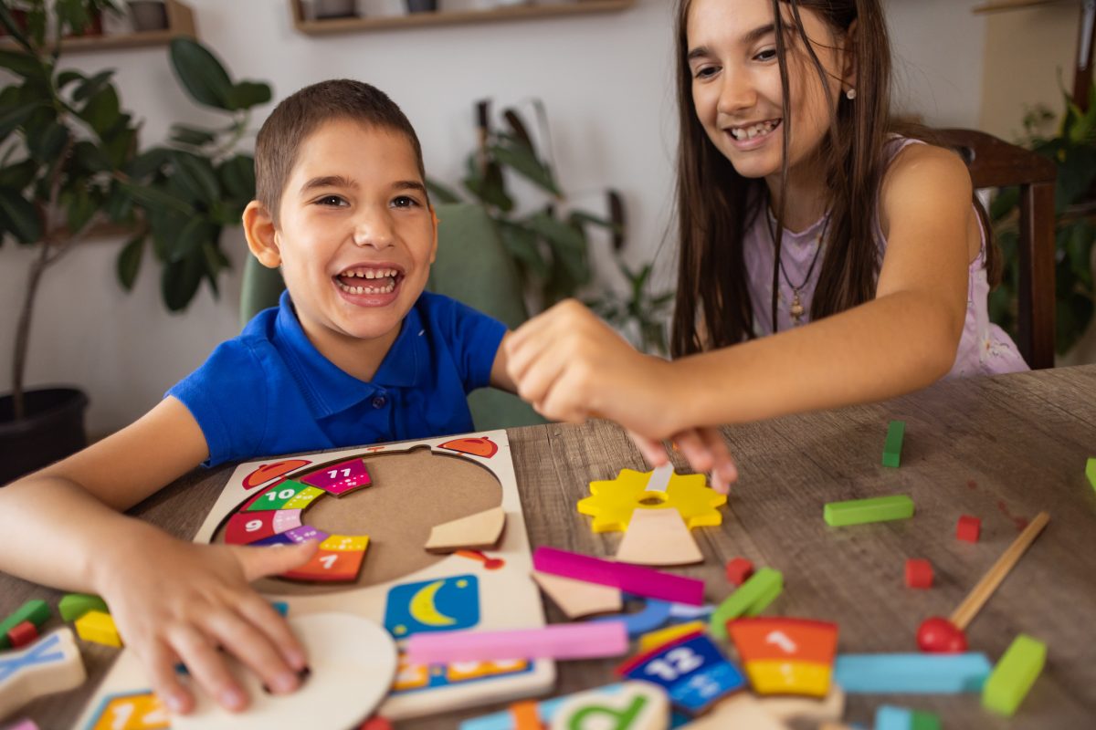 young boy with autism using sensory toys while playing with his sister