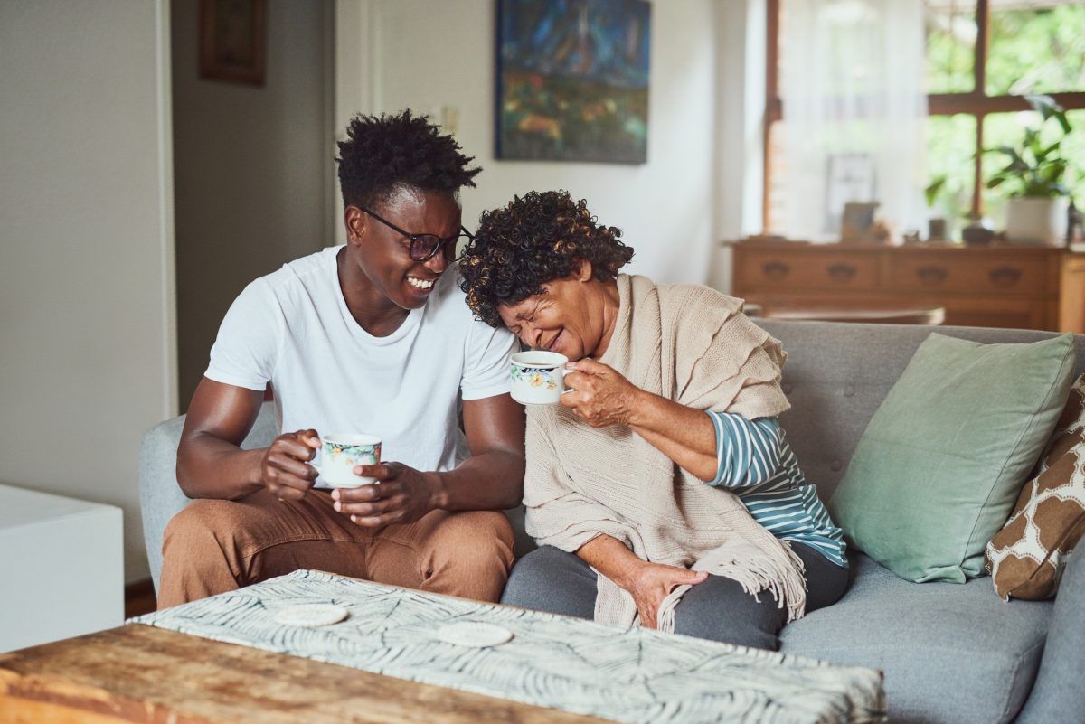 a young respite caregiver sitting on the couch with the woman he is taking care of